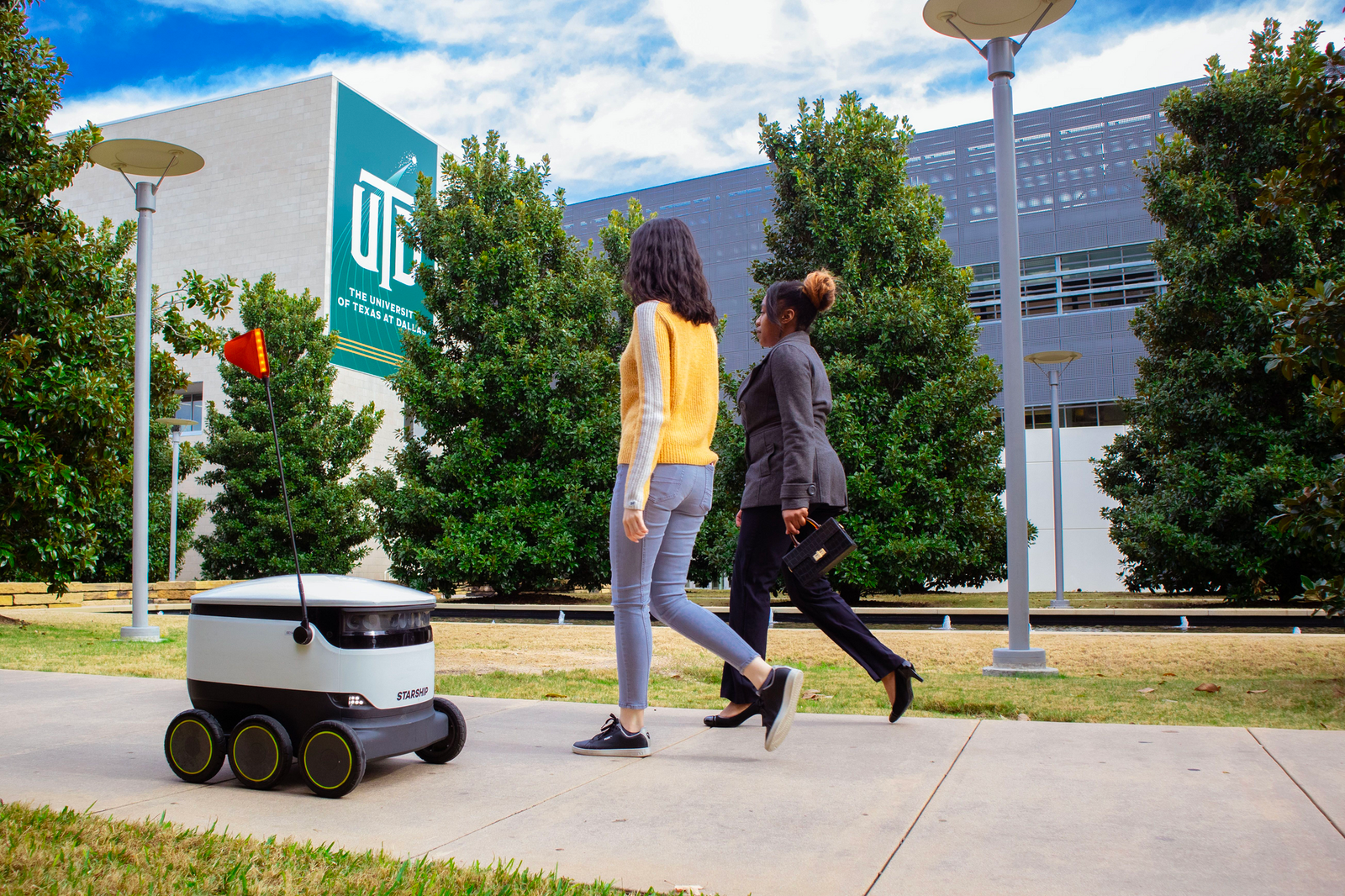 A Starship Technologies delivery robot moves along a walking path.