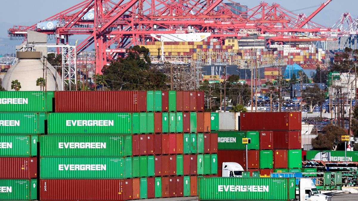 A truck drives past shipping containers stacked at the Port of Los Angeles.